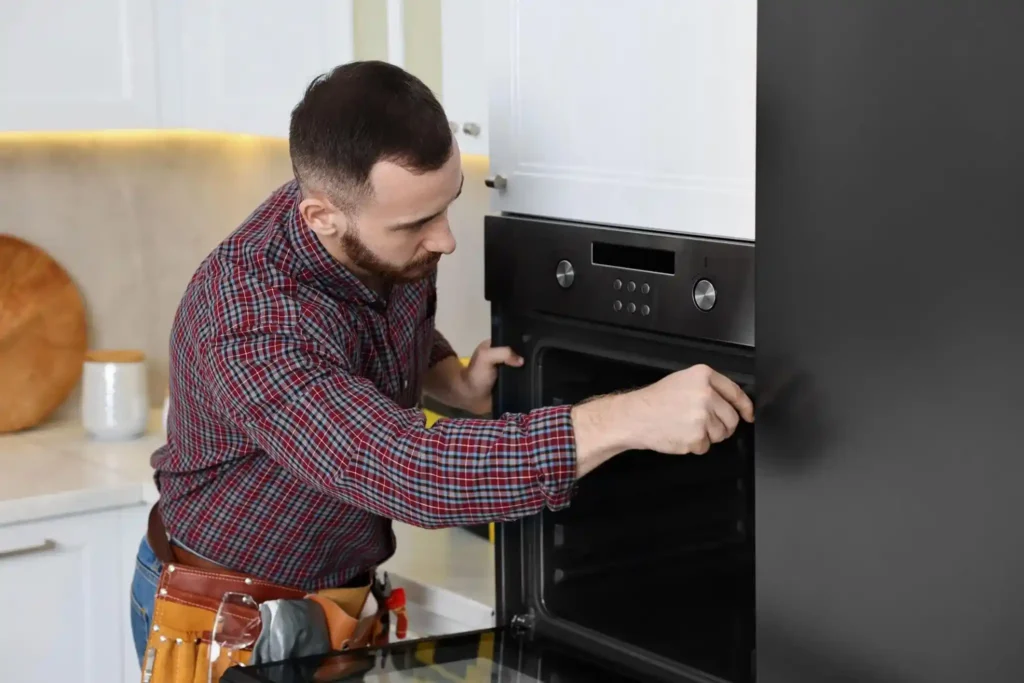 technician repairing built-in oven in modern kitchen during home service
